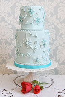 Blue cake embellished with blue sugar flowers.